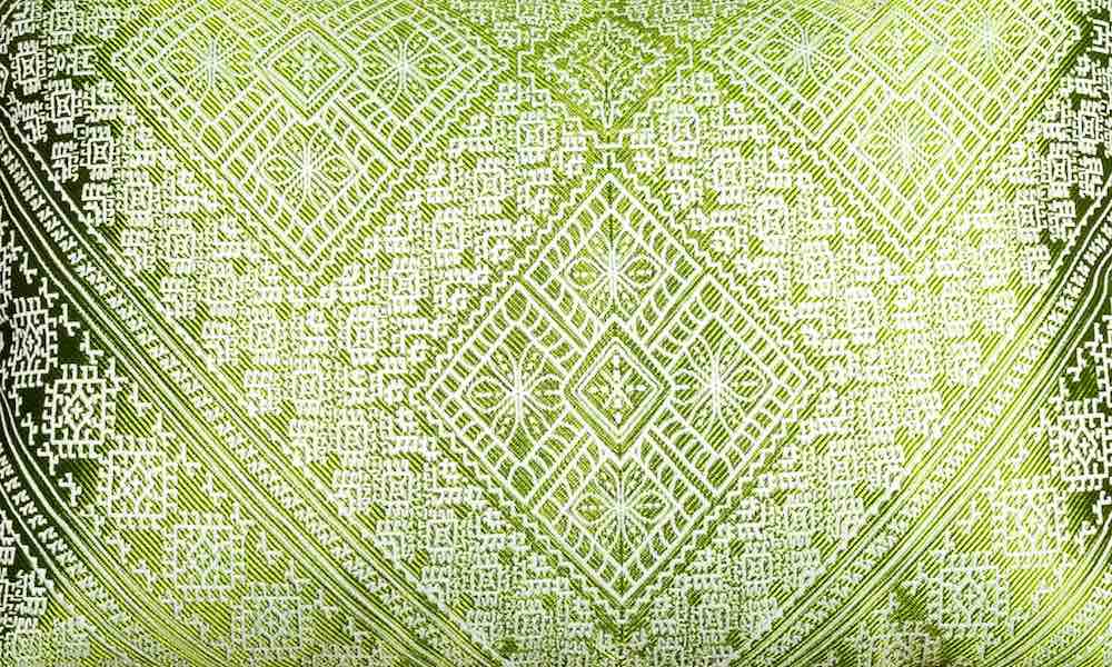 Nahaufnahme eines grünen Fluffikon Seidekissens. Das Kissen hat traditionelle marokkanische Muster.