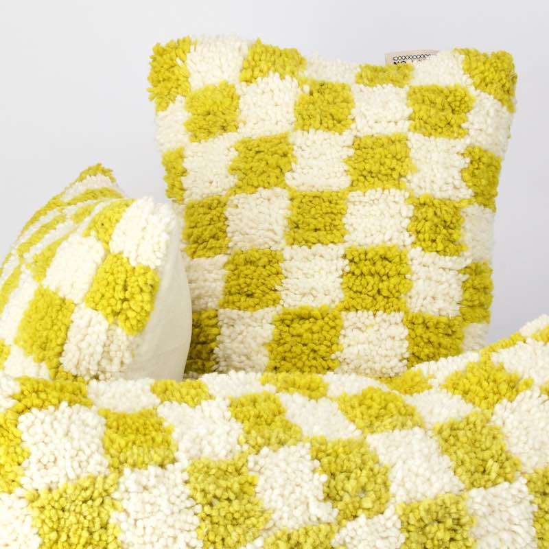 Three Beni Ourain with yellow and white checkered patterns are shown. The pillows are made from wool and look very fluffy.