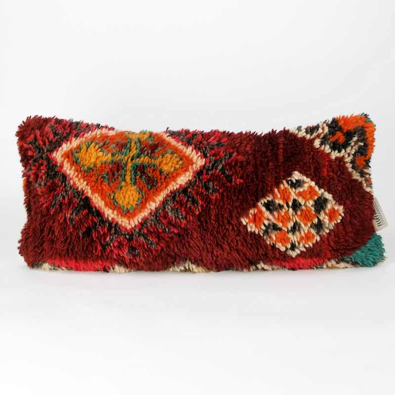 Ein dunkelrotes Vintage Berber Kissen stehen vor einem weissen Hintergrund. Das Kissen hat typisch marokkanische Muster.