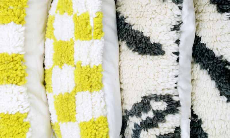 Zoom on yellow and black/white Fluffikon rug pillows made from Moroccan Berber rugs.
