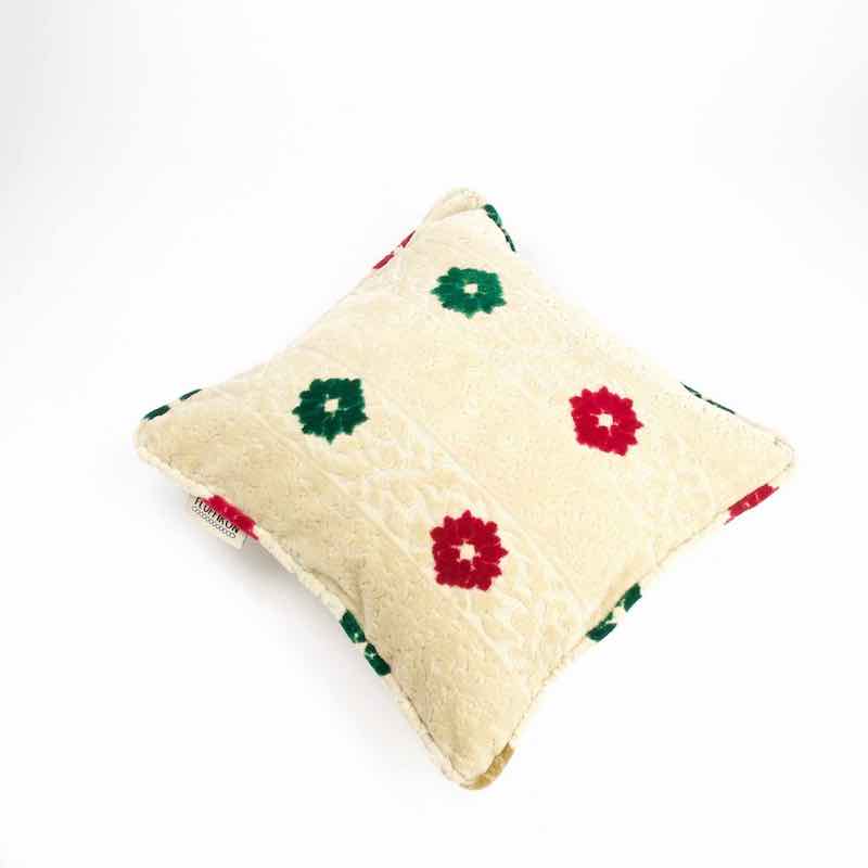 Marokkanisches beiges Sofakissen mit Blumen aus Samt vor weissem Hintergrund. 