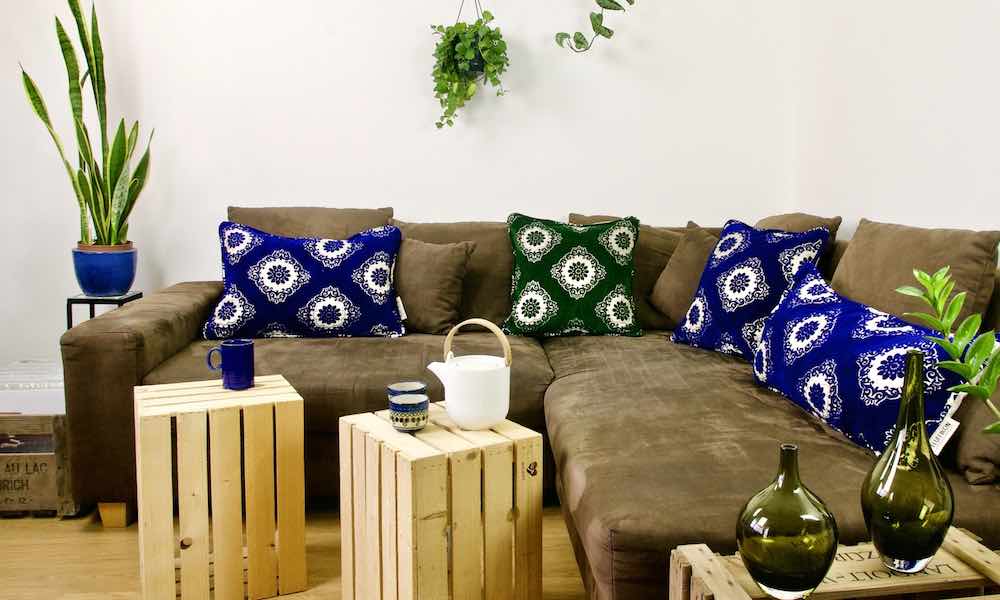 One green and three blue Moroccan pillows on a brown couch.