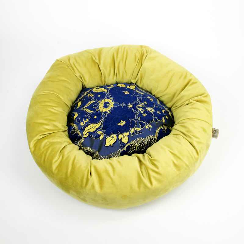 Blue golden Fluffikon dog bed in front of white background. The wool-filled dog is made from velvet fabrics.
