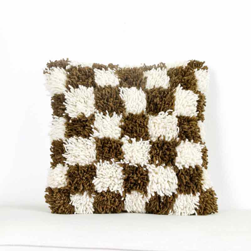 Earthly brown checkered Fluffikon Berber pillow in front of white background.
