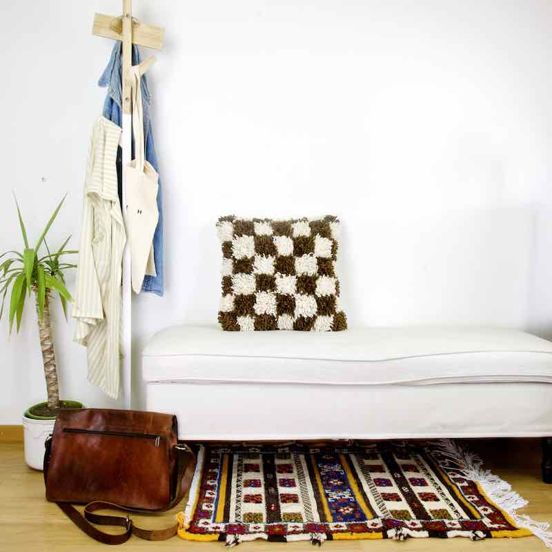 Earthly brown checkered Fluffikon Berber pillow on a white bench in a living room.