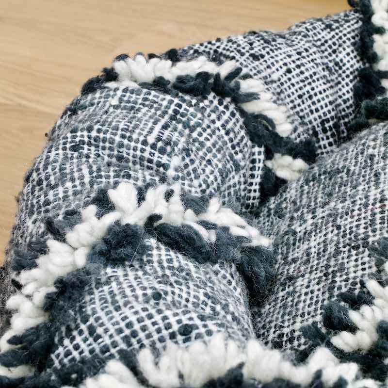 Zoom on a customized dog bed that is made from a black and white Moroccan Kilim wool rug.