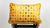 Mustard yellow Fluffikon cushion on wooden box.