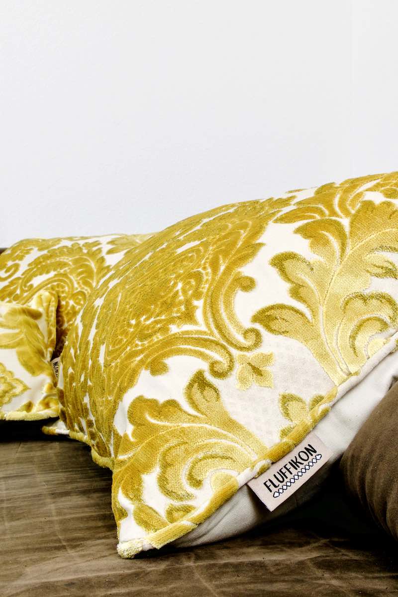 Zoom on a golden Fluffikon velvet pillow on a brown sofa. The pillow has traditional Moroccan patterns. 