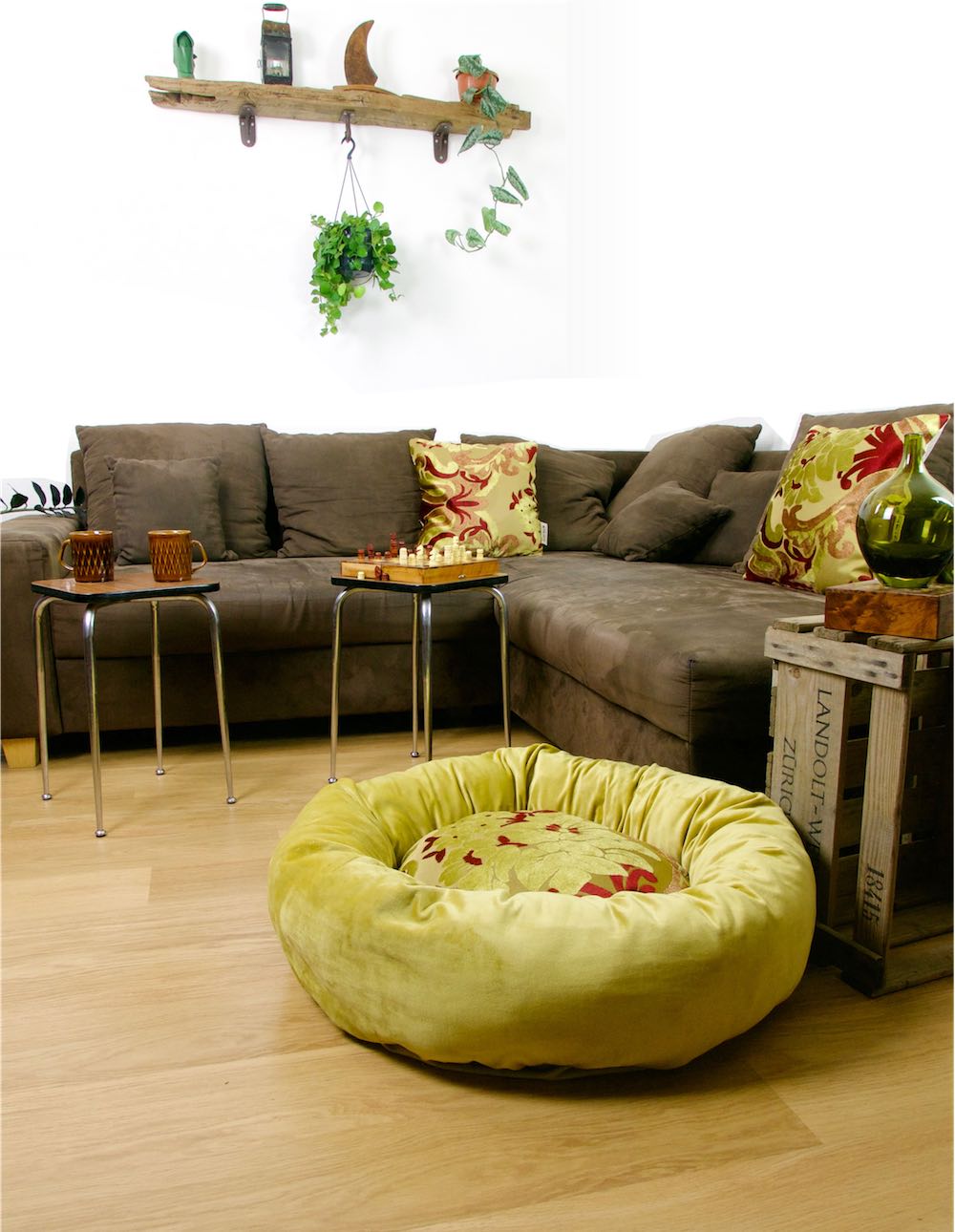 Red golden donut pet bed in an stylish living room. Two decorative pillows on the couch are made from the same material as the pet bed.