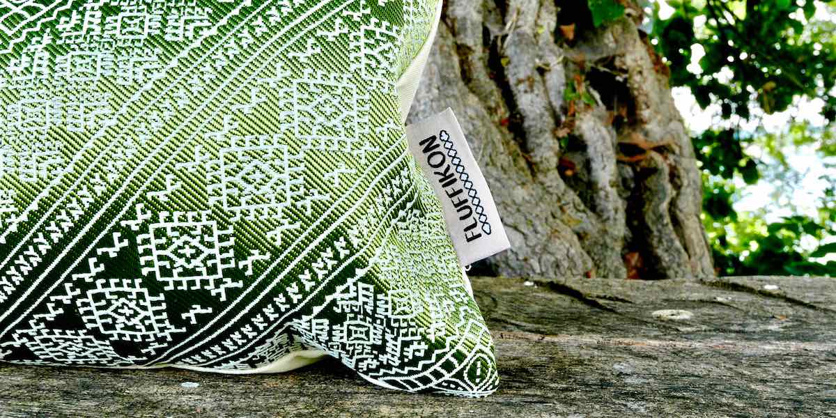 Zoom on a green Moroccan pillow on a wooden bench. The Fluffikon label can be seen.