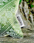 Zoom on a green Moroccan pillow on a wooden bench. The Fluffikon label of the lumbar pillow can be seen.