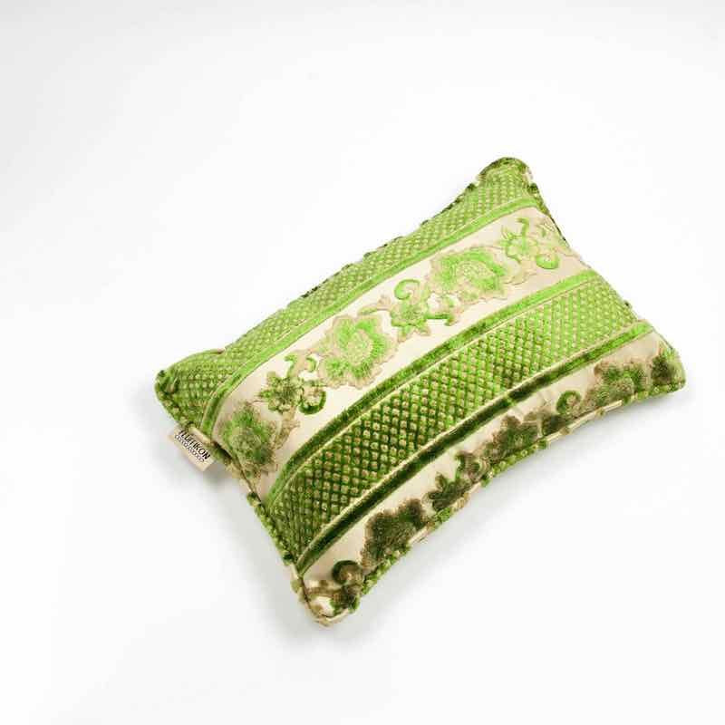 Green moroccan velvet cushion in front of white background.