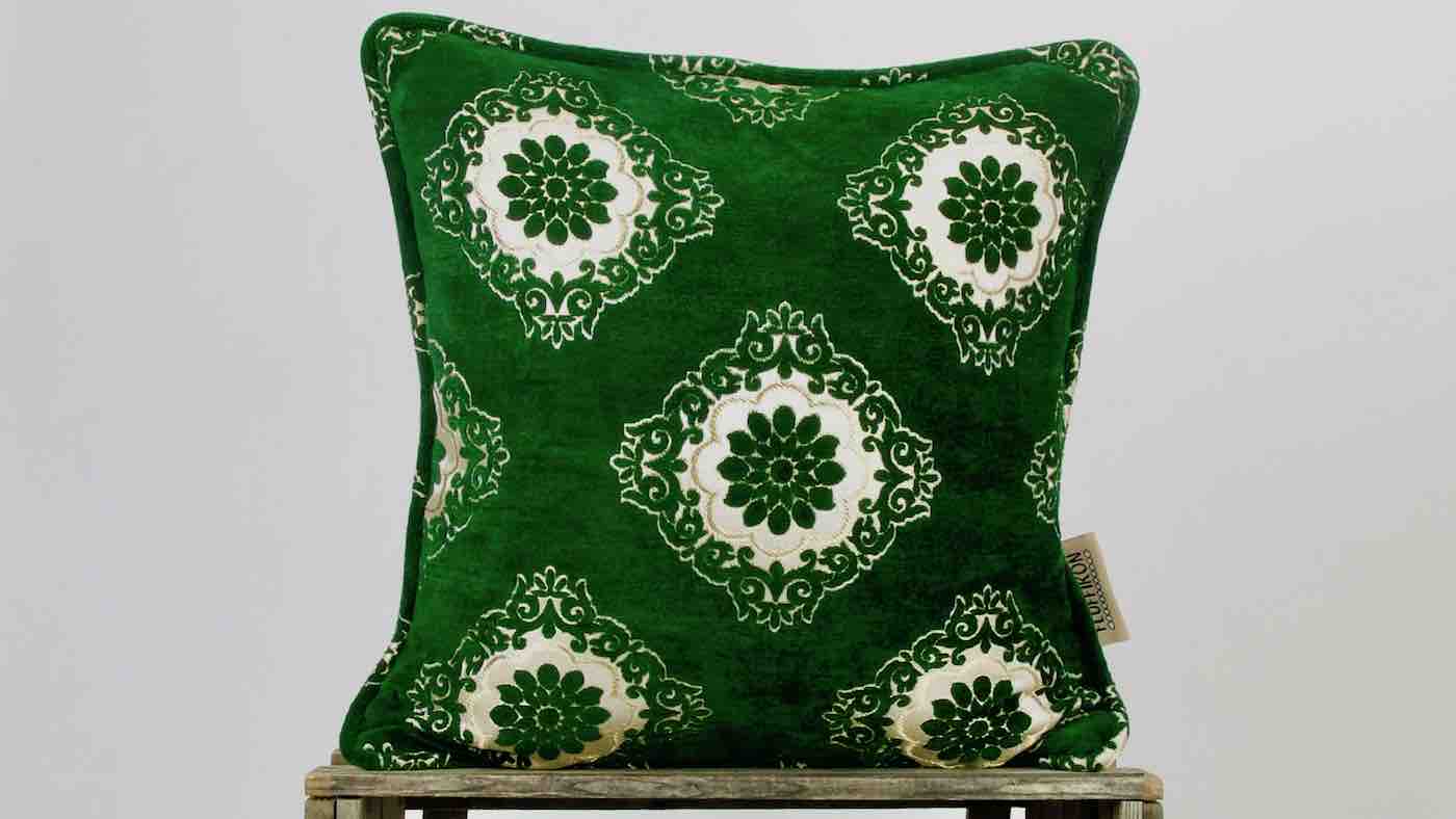 Fluffikon green velvet pillow. The cushion is standing on a wooden box.