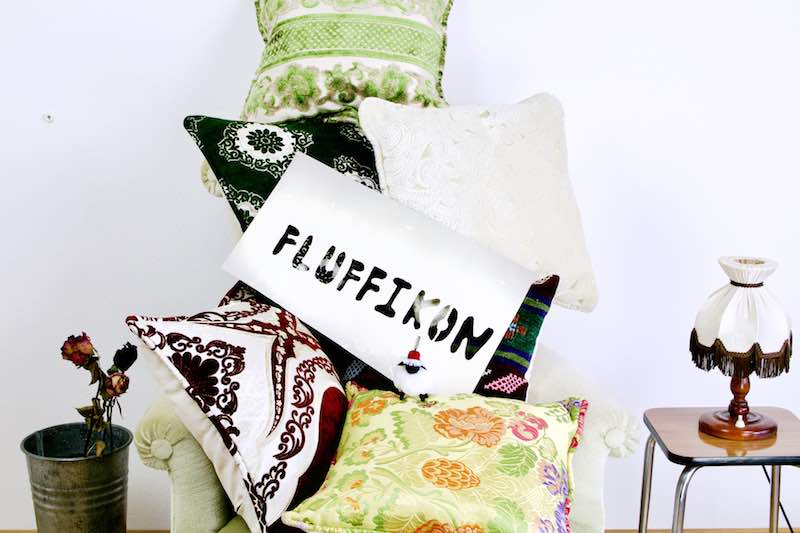 Multiple Fluffikon throw pillows on a chair.