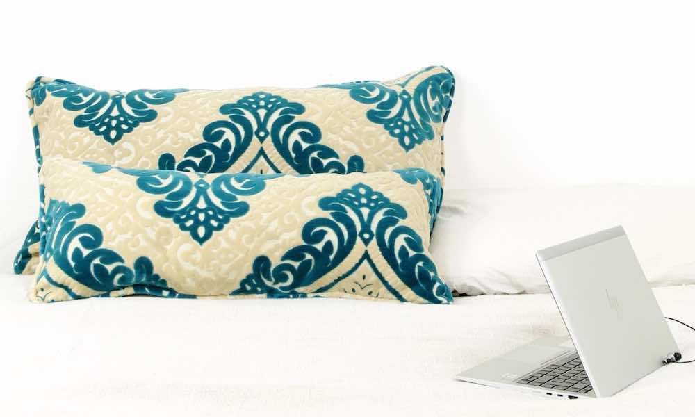 Two large throw pillows on a white bed.