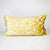 Gold oversized Fluffikon couch pillow standing in front of white background.