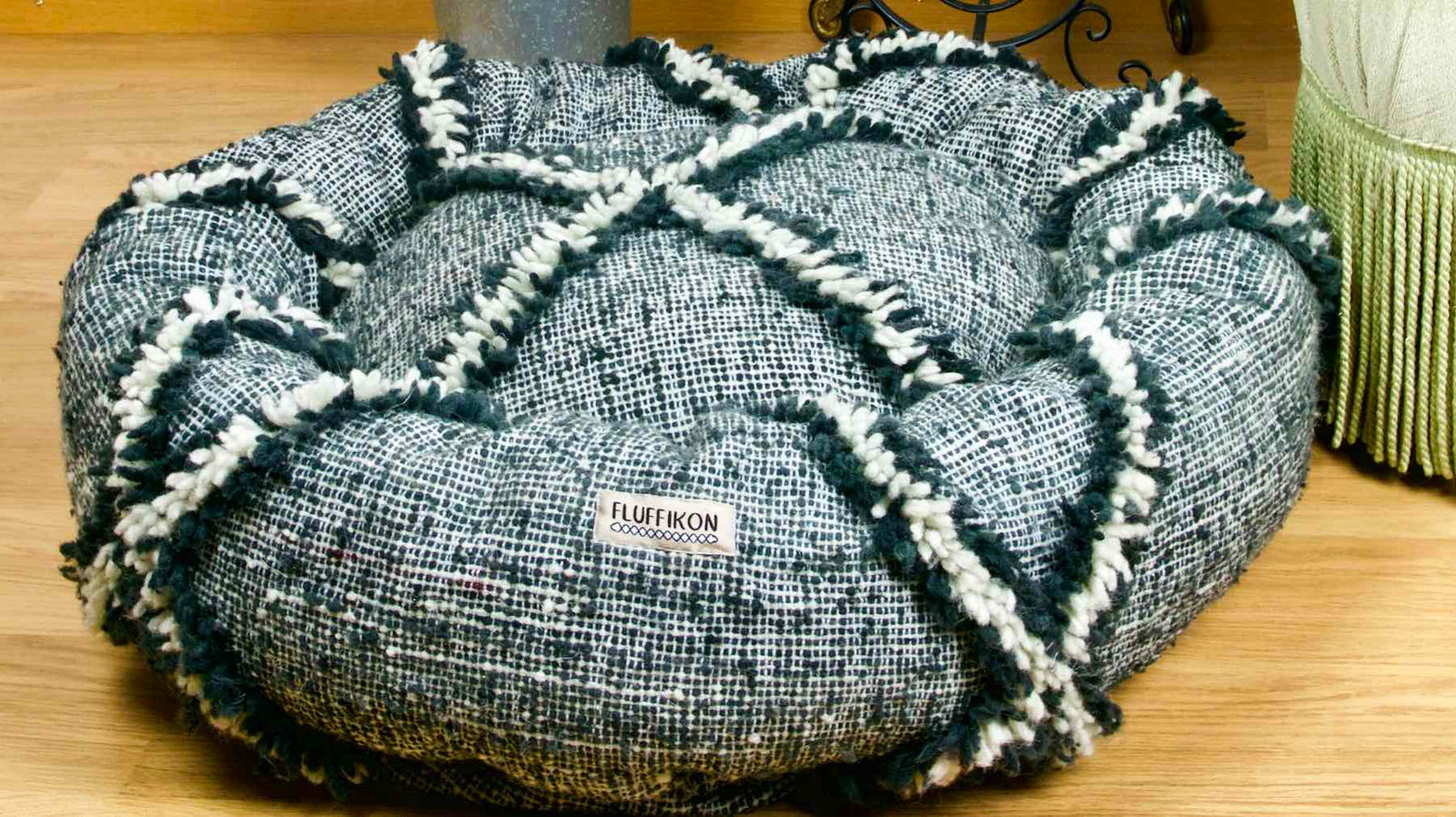 Kilim dog bed in front of a green velvet chair. The customized dog bed is made from a Moroccan Kilim wool rug.