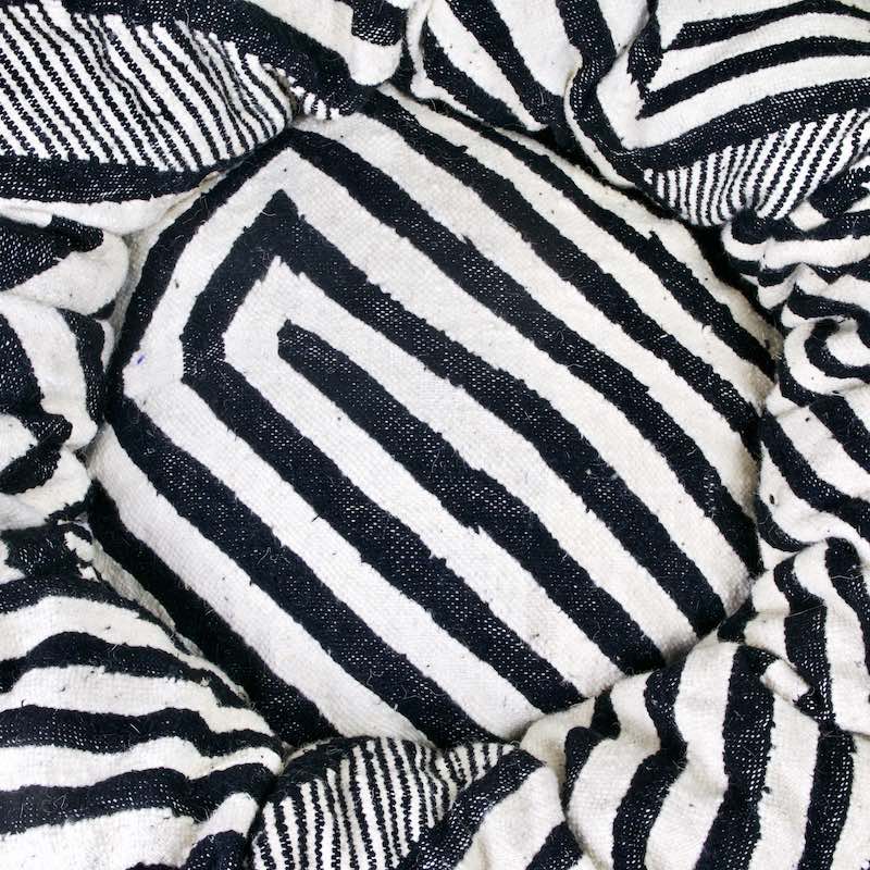 Zoom auf schwarz weisses Kelim Fluffikon Katzenbett. Der Stoff hat die Muster eines Zebras.