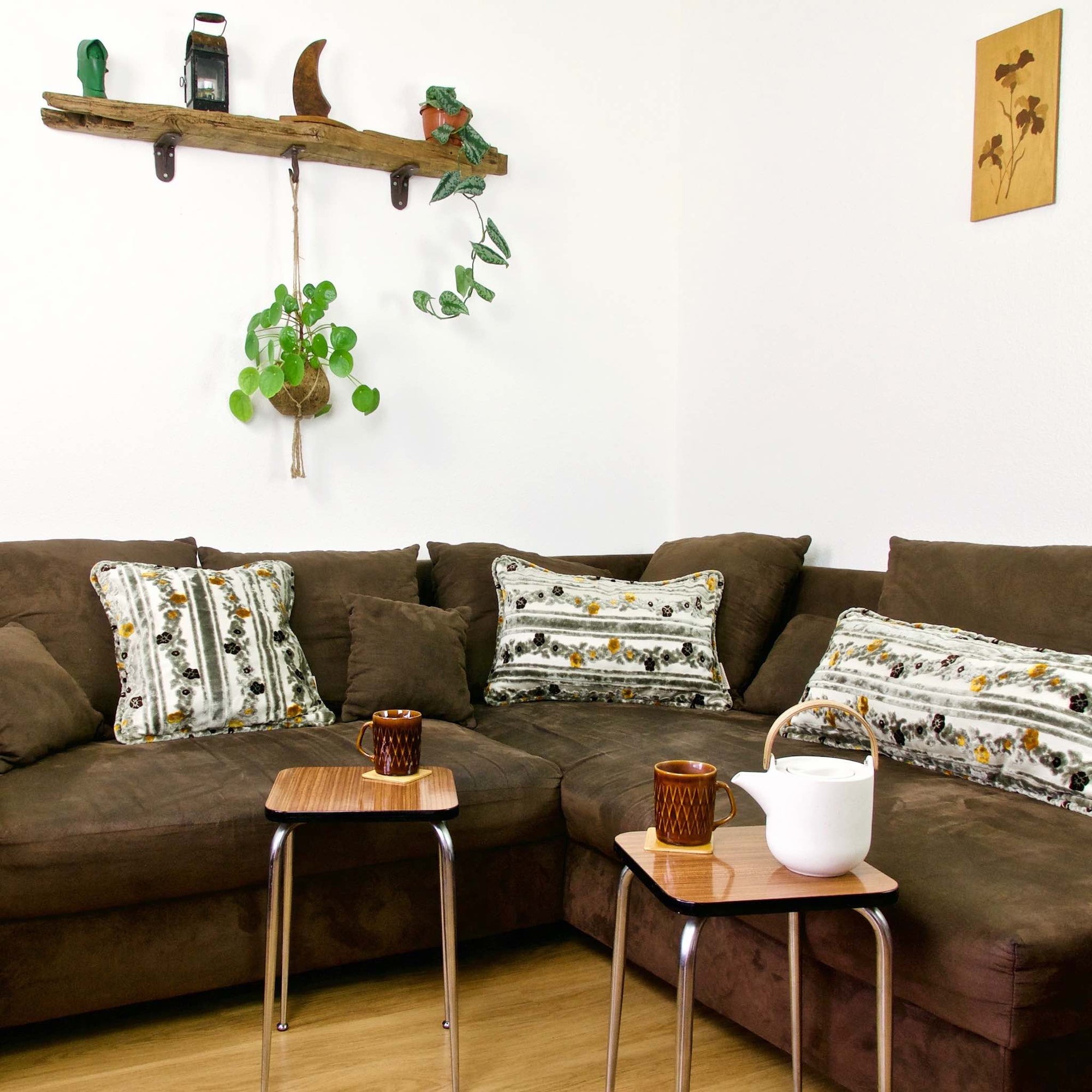 Three Cinnamon Love pillows on a brown couch in a living room.