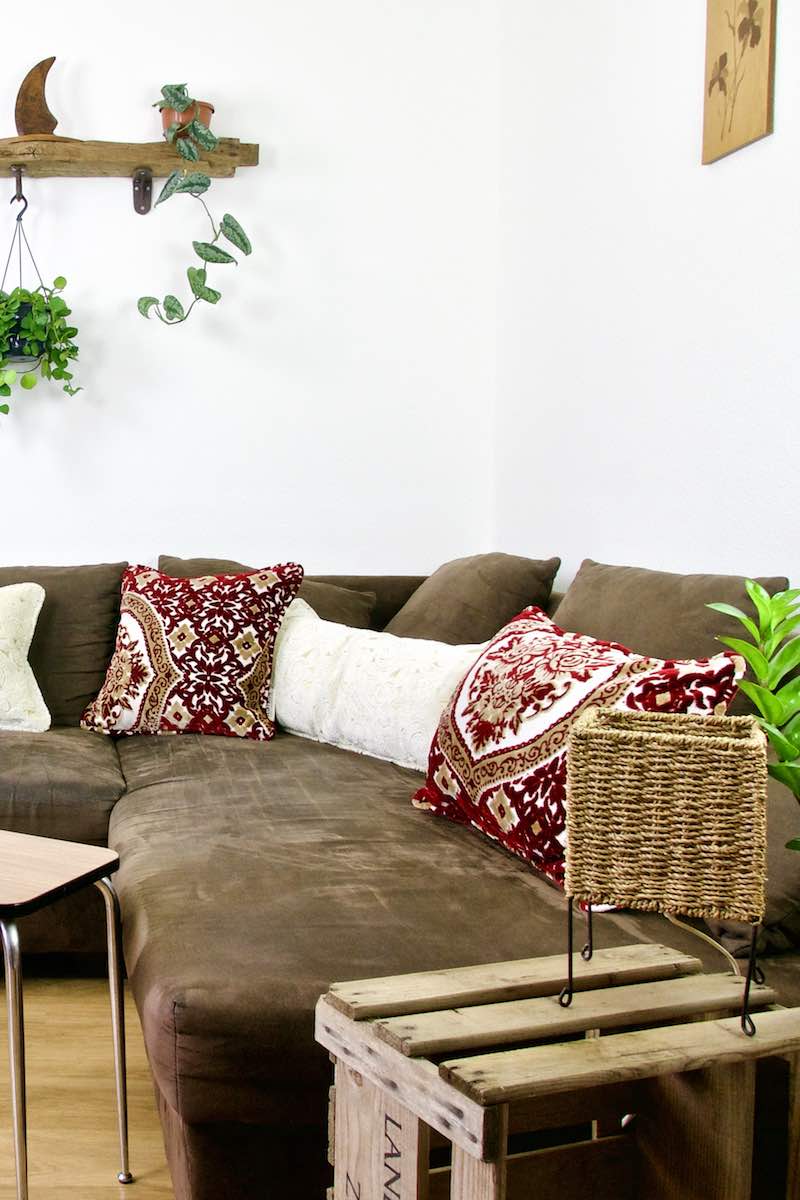Three Moroccan throw pillows on a brown sofa. Two pillows are red and have traditional Moroccan patterns.