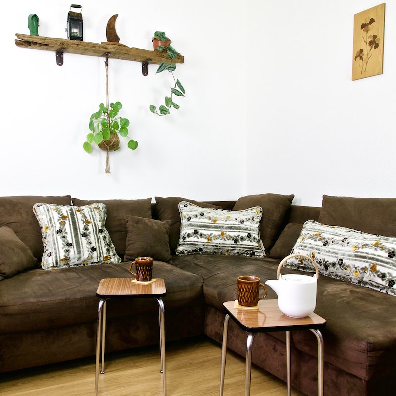 Three grey Fluffikon Moroccan throw pillows are standing on a brown couch.
