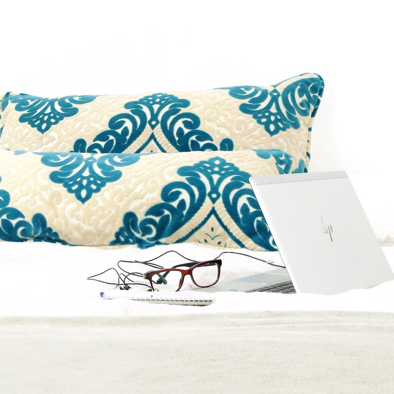 Two Moroccan large pillows on a bed. The turquoise pillows have traditional Moroccan patterns.