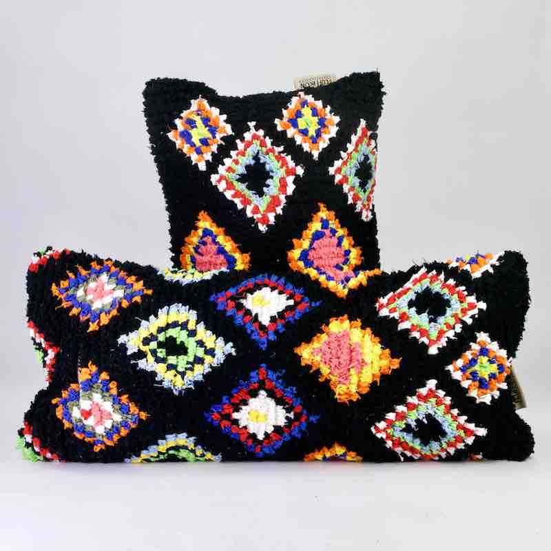 Two black Boucherouite Fluffikon throw pillows with colorful spots.