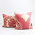 Two blush pink Fluffikon throw pillows with a golden floral pattern in front of each other.