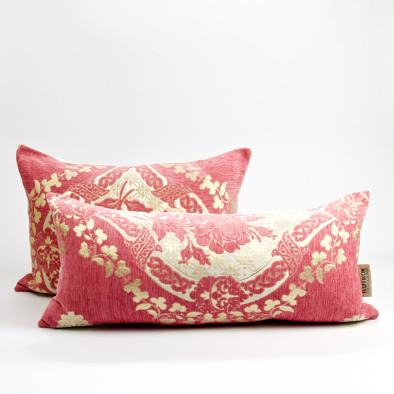 Two blush pink Fluffikon lumbar pillows with golden flower motif. The lumbar pillows have a traditional Moroccan design.