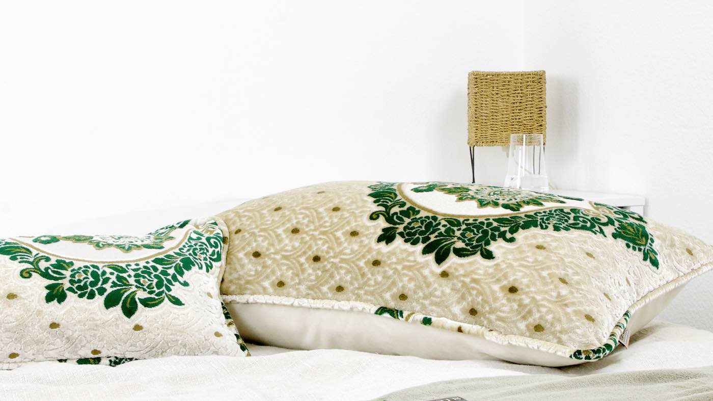 Two oriental Fluffikon pillows on a bed. The lumbar pillow and the XXL pillow have a green and brown typical Moroccan pattern.