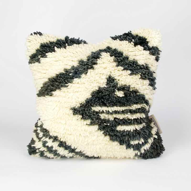 Ein schwarz weisses vintage Teppichkissen vor weissem Hintergrund.