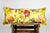Yellow Fluffikon brocade pillow on a wooden box.