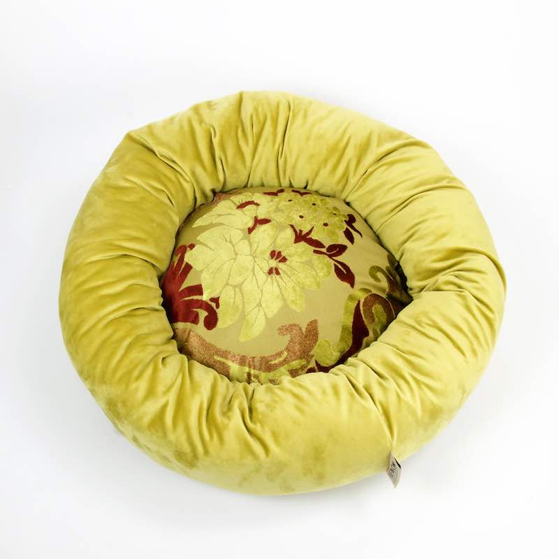 Fluffikon donut dog bed in front of white background. The dog bed is made from golden, yellow and red velvet fabrics.