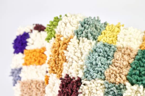 Zoom on the corner of a colorful Fluffikon wool pillow.