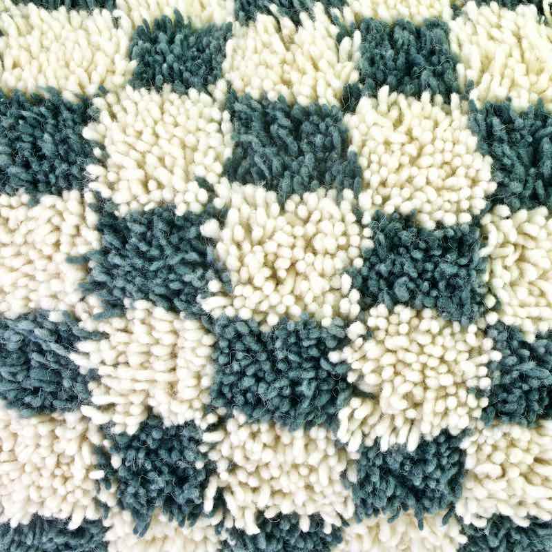 Zoom on a gray white Fluffikon checkered throw pillow made from a Moroccan wool rug.