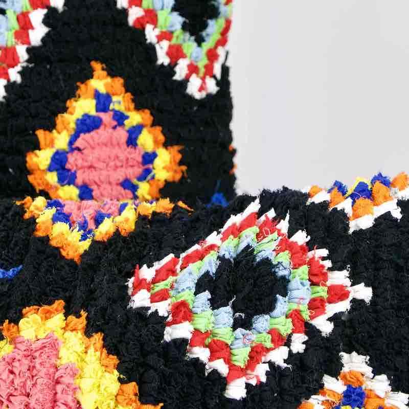 Zoom on two black Boucherouite Fluffikon throw pillows. The pillows have colorful spots.