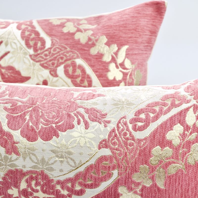 Zoom on two blush pink Fluffikon throw pillows with a golden floral pattern.