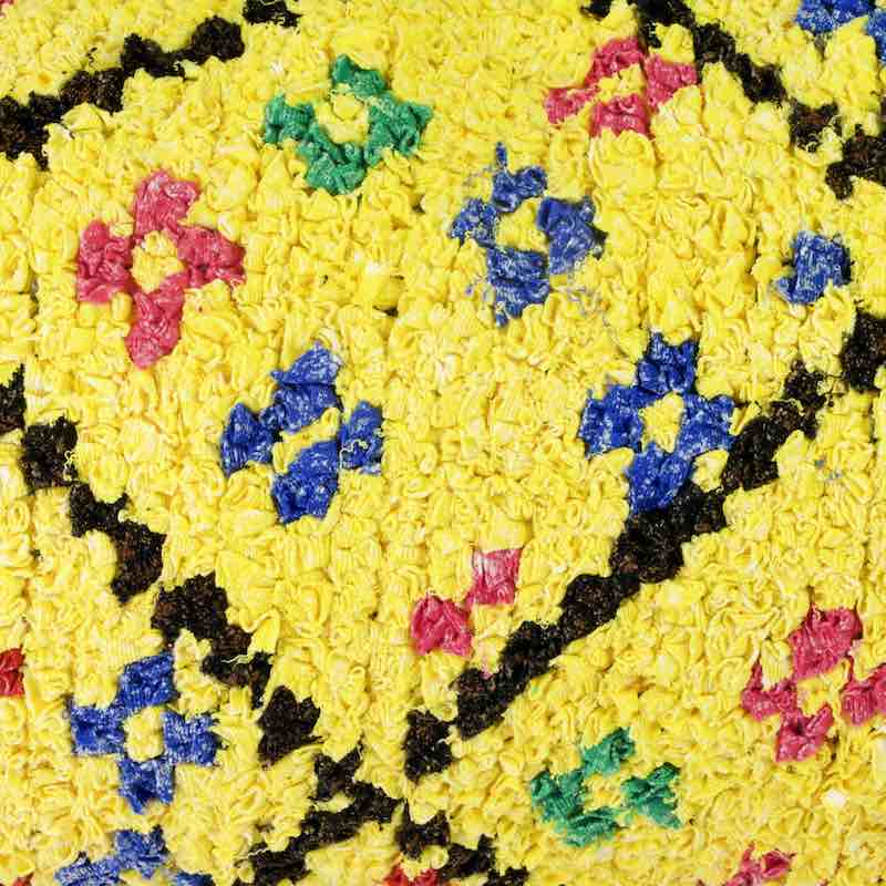 Zoomed view on yellow Boucherouite Berber cushion cover. The pillow is yellow but has little colorful flowers.