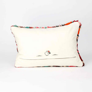 A red rectangular Berber pillow made from a vintage rug is standing in front of a white background. The cushion is shown from the back.