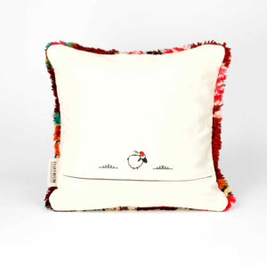 The back of a standing red Berber pillow made from a vintage wool rug.