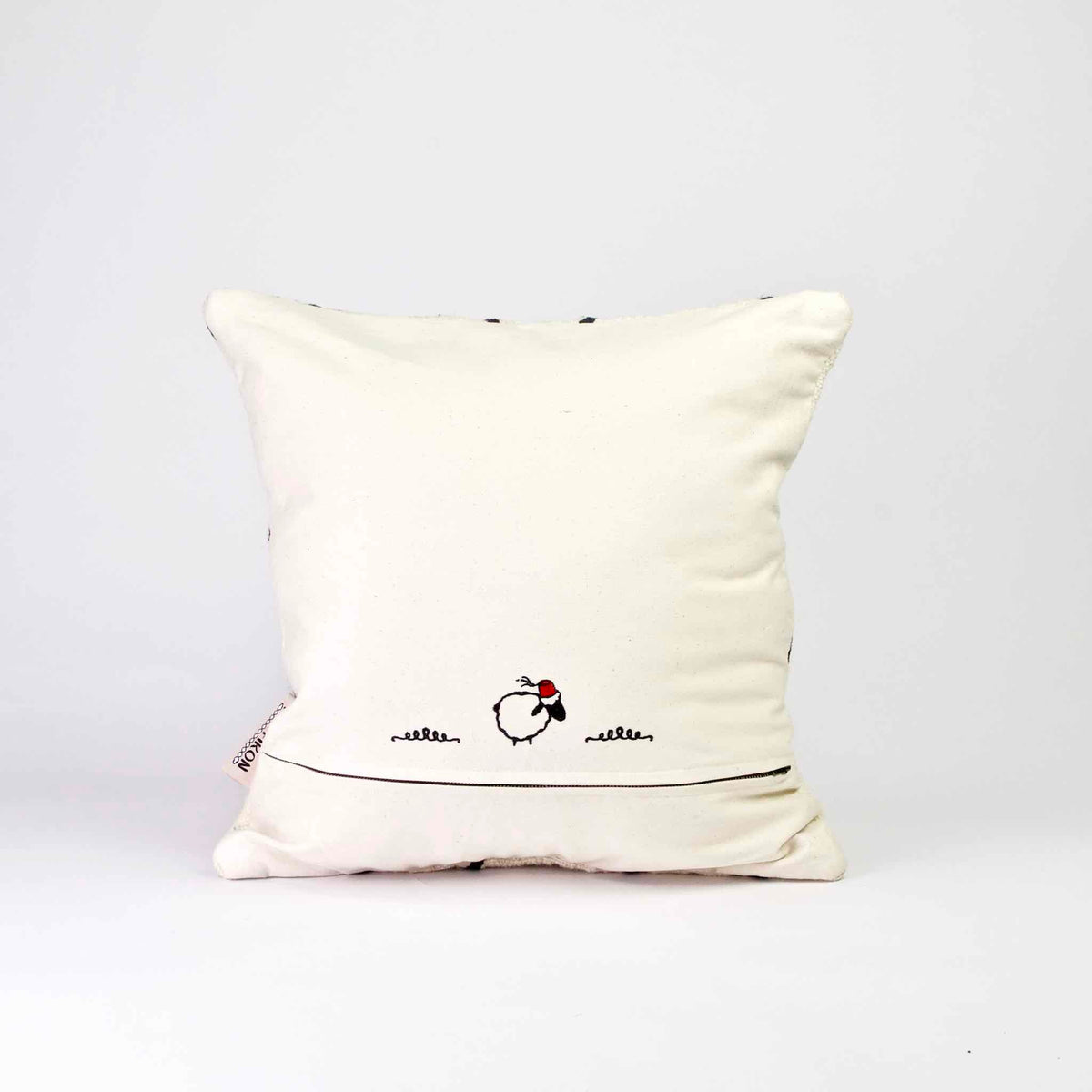 The back of a square Fluffikon Kilim pillow cover. The pillows stands in front of a white background.