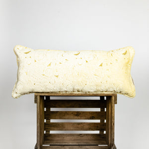 Fluffikon velvet lumbar pillow made from beige moroccan fabric. The pillow is on a wooden box.