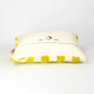 Beni Ourain Fluffikon pillow laying on the ground. The cushion is made from a yellow-white checkered wool rug.