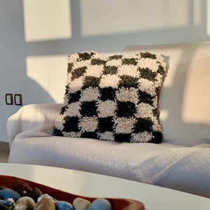 Checkered Moroccan Fluffikon pillow standing on a couch. The photo is taken during sunset lights.