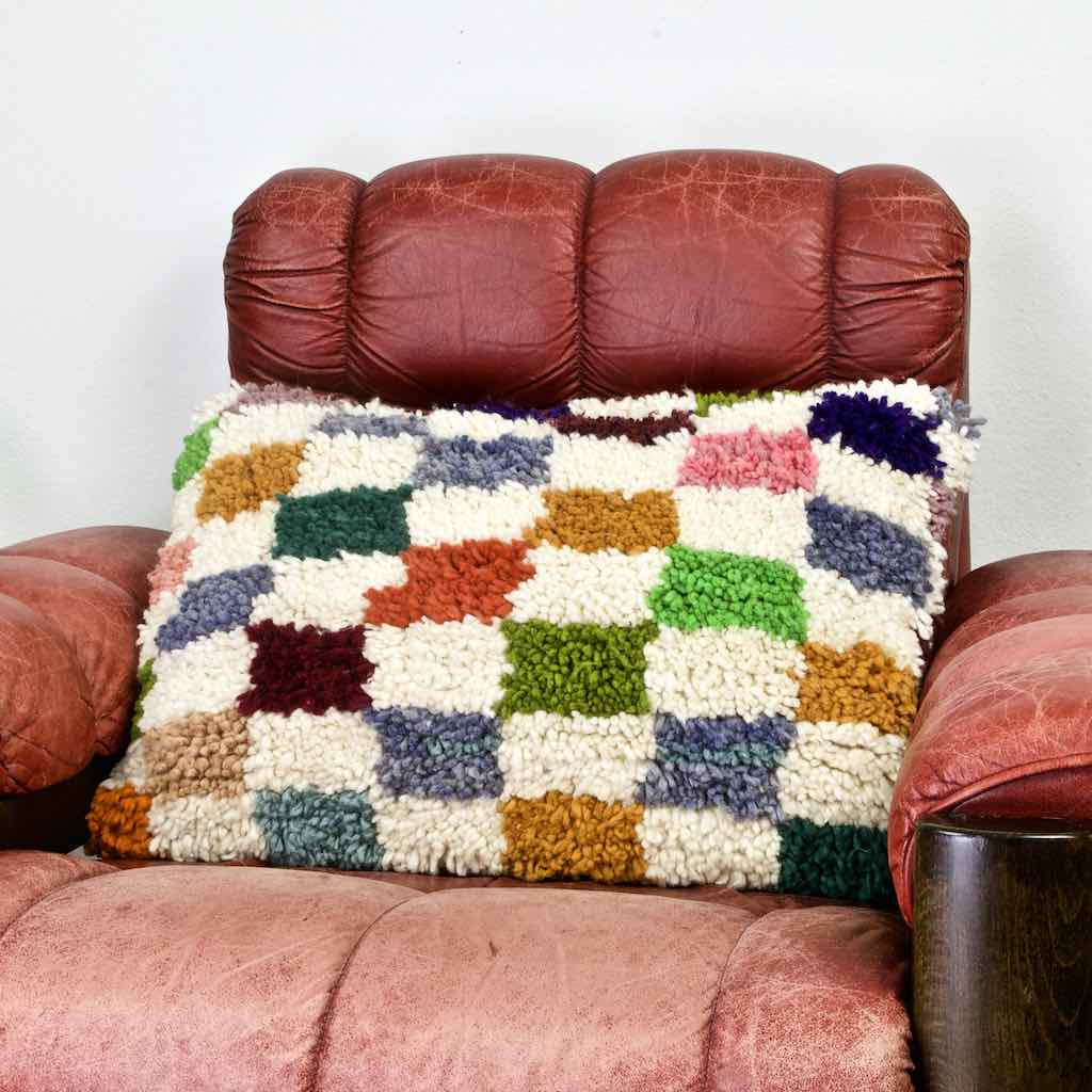 Zoom of Colorful checkered throw Pillow on a red leather chair