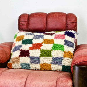 Zoom of Colorful checkered throw Pillow on a red leather chair