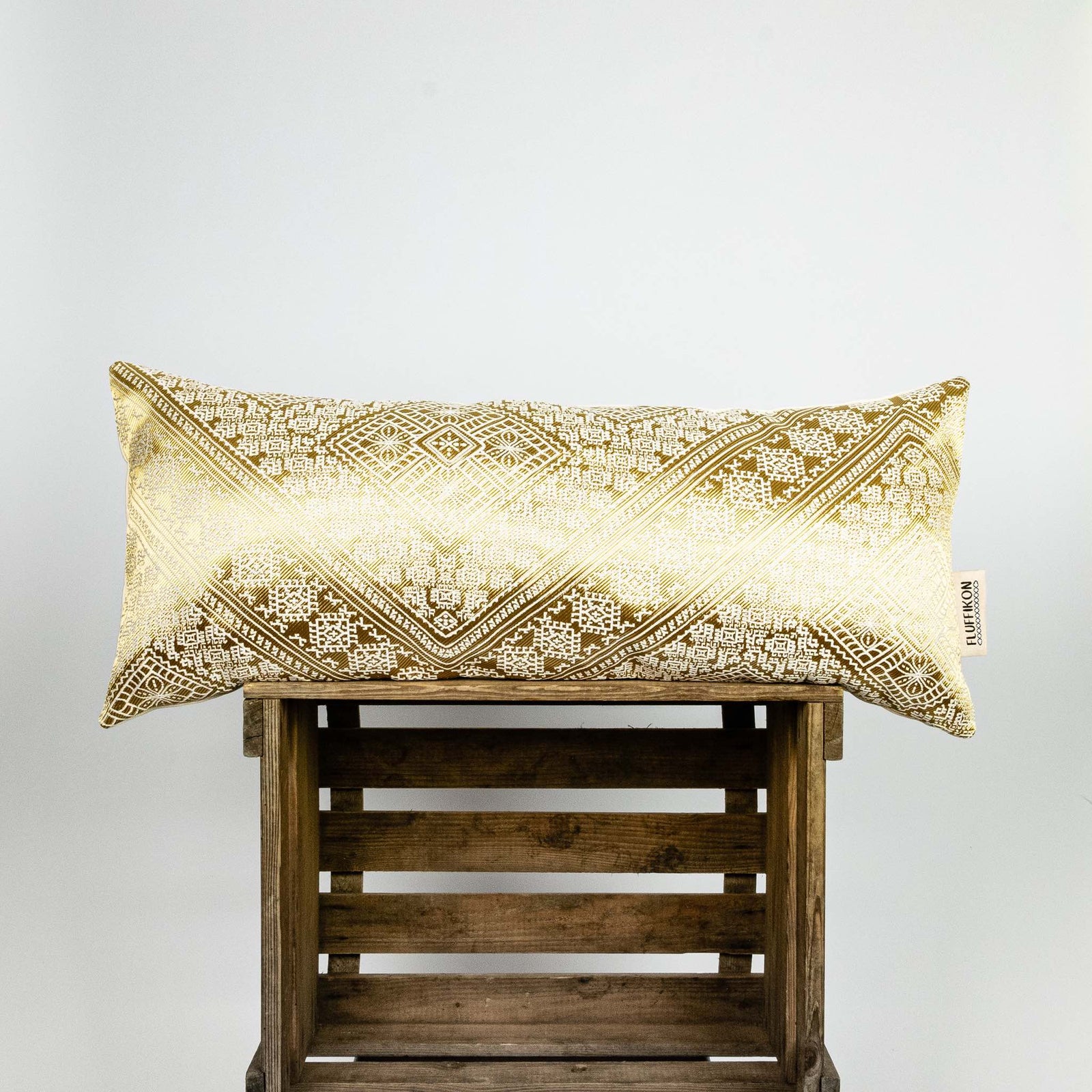 Sofakissen Gold aus Seide. Das goldene Fluffikon Kissen hat typische marokkanische Muster. Es steht auf einer Holzbox.