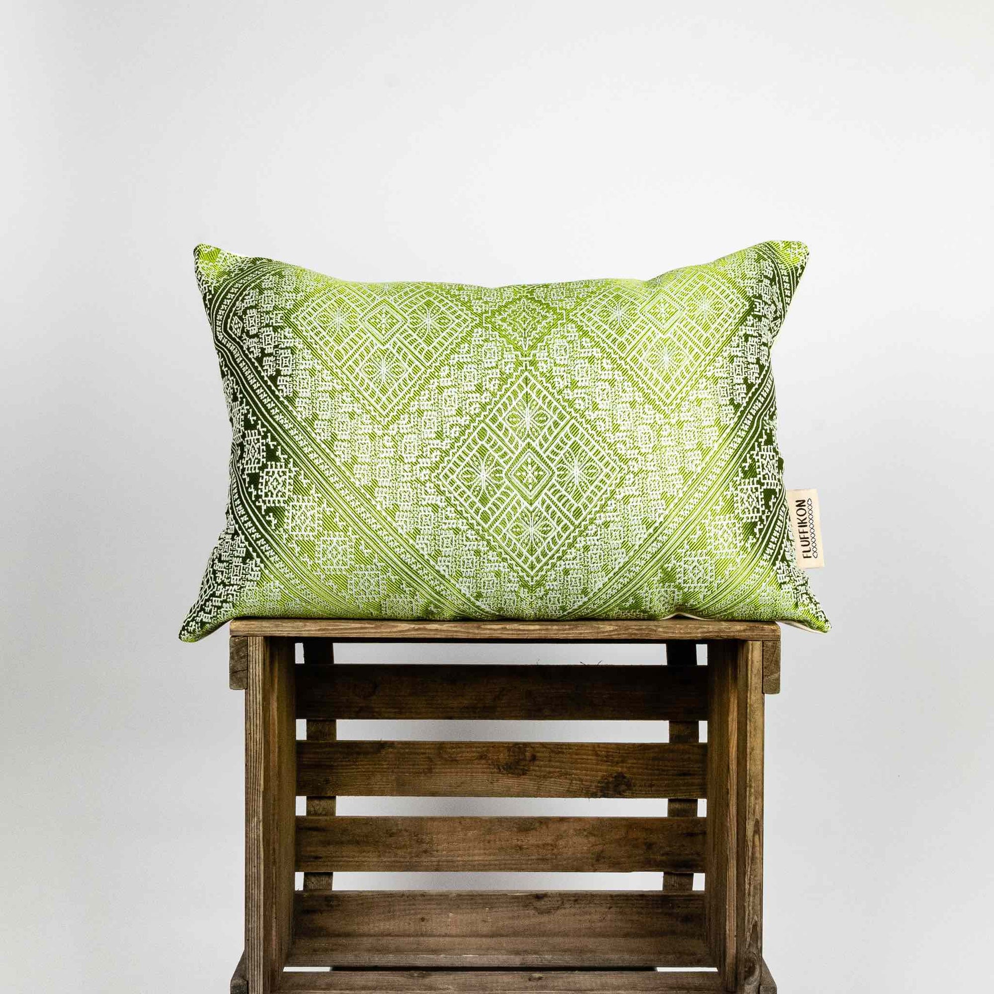 Large decorative pillow made from green moroccan silk fabric. The pillow is on a wooden box. Size 40x60 cm.