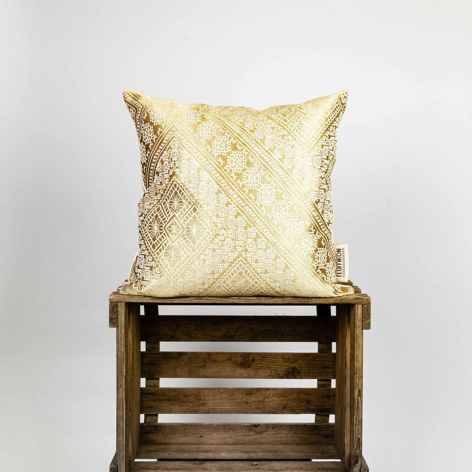 Zierkissen Gold auf einer Holzbox. Das goldene Kissen hat typische marokkanische Muster.