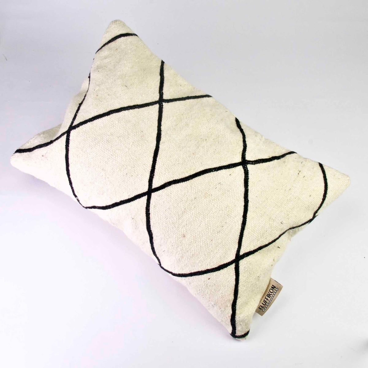 Black and white Fluffikon Kilim throw pillow on a white floor.